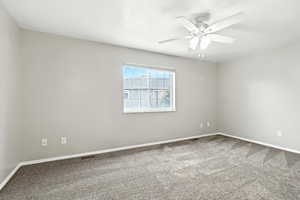 Carpeted empty room featuring baseboards and a ceiling fan