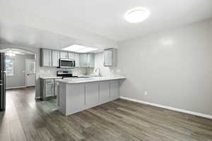 Kitchen featuring gray cabinetry, a peninsula, and dark wood-type flooring