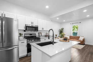 Kitchen with stainless steel appliances, white cabinetry, light stone countertops, dark wood-style flooring, and recessed lighting