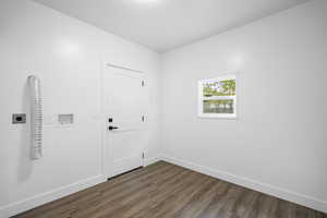 Empty room with dark wood-type flooring and baseboards