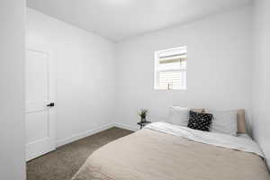 Bedroom with dark colored carpet and baseboards