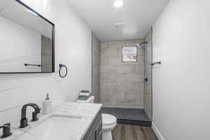 Bathroom featuring vanity, a stall shower, dark wood finished floors, and a textured ceiling