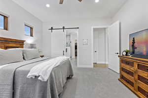 Bedroom featuring a barn door, recessed lighting, light colored carpet, ensuite bathroom, and ceiling fan