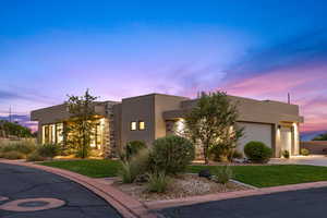 View of front of home featuring a garage, stucco siding, a front yard, and concrete driveway