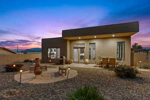 Back of property at dusk featuring a patio and stucco siding