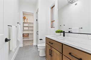 Bathroom with vanity, light tile patterned floors, a stall shower, and a closet