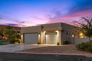 View of front facade with an attached garage, driveway, and stucco siding