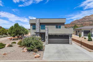 Contemporary house with concrete driveway, stone siding, stucco siding, and a mountain view