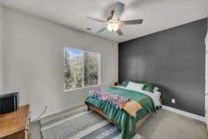 Bedroom with a ceiling fan, carpet floors, a textured ceiling, and an office area