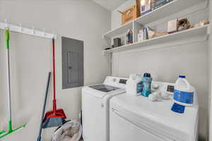 Washroom featuring electric panel and washing machine and dryer