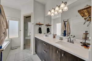 Full bath with light tile patterned flooring, double vanity, a shower stall, and a garden tub