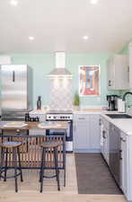 Kitchen with stainless steel appliances, island exhaust hood, light wood-type flooring, recessed lighting, and white cabinets