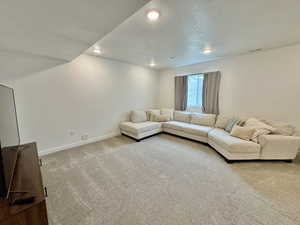 Living room with light carpet, a textured ceiling, and recessed lighting