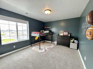 Carpeted bedroom featuring baseboards and a textured ceiling