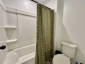 Full bathroom with toilet and shower / bathtub combination with curtain