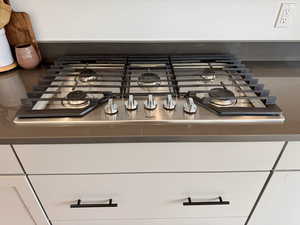 Kitchen view of stainless steel gas cooktop and white cabinets