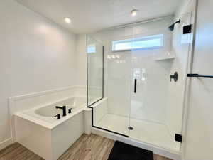 Full bath with a garden tub, a shower stall, light wood finished floors, and a textured ceiling