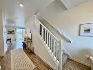 Stairs featuring wood finished floors, a textured ceiling, and recessed lighting