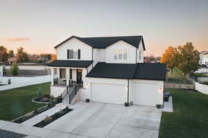 Modern inspired farmhouse featuring board and batten siding, a porch, and driveway