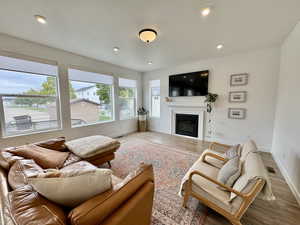Living area featuring a glass covered fireplace, wood finished floors, and recessed lighting