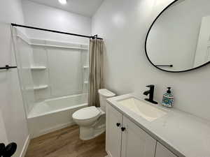 Full bath featuring shower / tub combo, vanity, and dark wood-type flooring