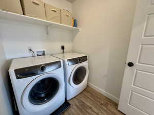 Washroom with wood finished floors and washer and dryer