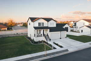 Modern inspired farmhouse featuring covered porch, board and batten siding, a residential view, and driveway