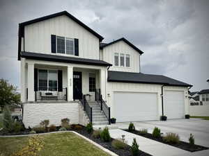 Modern inspired farmhouse featuring board and batten siding, a porch, concrete driveway, a shingled roof, and a front lawn