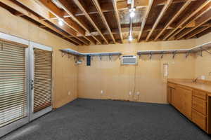 Below grade area featuring dark colored carpet and a wall mounted air conditioner