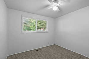 Carpeted empty room with ceiling fan and baseboards