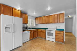 Kitchen featuring white appliances and brown cabinets