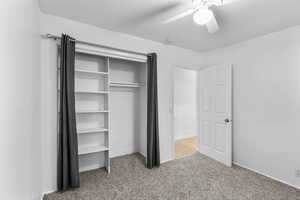 Unfurnished bedroom featuring light colored carpet, a ceiling fan, and a closet