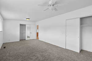 Unfurnished bedroom with two closets, carpet floors, and a ceiling fan