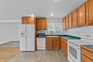 Kitchen with white appliances, brown cabinetry, and light tile patterned flooring
