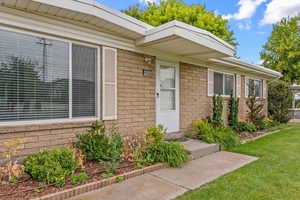 View of exterior entry with brick siding and a yard