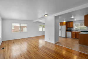 Unfurnished living room with light wood-style floors and beam ceiling