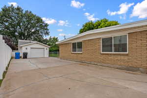 View of home's exterior featuring an outdoor structure, driveway, a detached garage, and brick siding