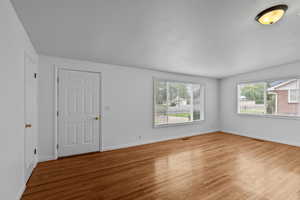 Unfurnished living room featuring wood finished floors and baseboards