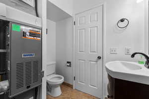 Half bathroom with vanity, heating unit, and light tile patterned floors