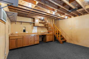Unfinished basement with stairs and dark carpet
