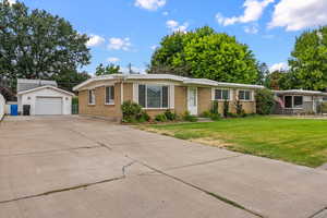 Ranch-style house featuring an outdoor structure, brick siding, a detached garage, concrete driveway, and a front yard
