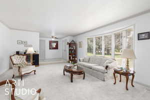 Formal living area featuring crown molding, carpet floors, and ceiling fan