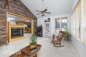 Sunroom with carpet floors, high vaulted ceiling, a multi sided fireplace, ceiling fan, and brick wall