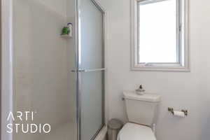 Bathroom with toilet and a shower stall - located off of the laundry room