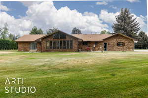 View of back of property featuring a front yard, brick siding, and roof with shingles