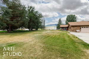 View of grassy yard with a mountain view, a garage, and driveway
