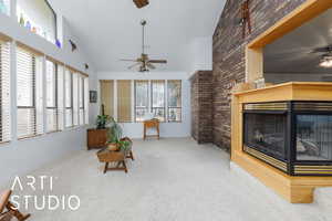Sunroom featuring a ceiling fan, a multi sided fireplace, carpet floors, high vaulted ceiling, and brick wall