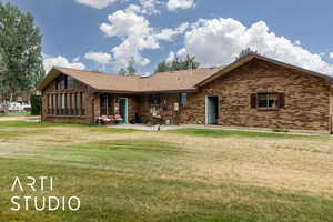 Back of house featuring brick siding, a yard, a shingled roof, and a patio