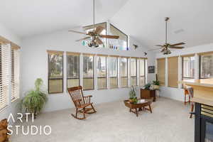 Sunroom featuring carpet floors, plenty of natural light, and high vaulted ceiling