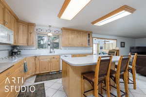 Kitchen featuring a kitchen breakfast bar, decorative backsplash, light tile patterned floors, and light countertops